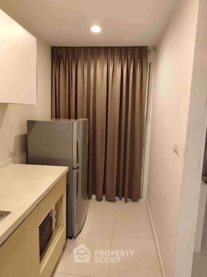 Modern kitchen with sleek appliances and elegant curtains in a compact space.