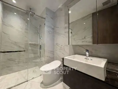 Luxurious modern bathroom with sleek marble finishes and glass shower enclosure.