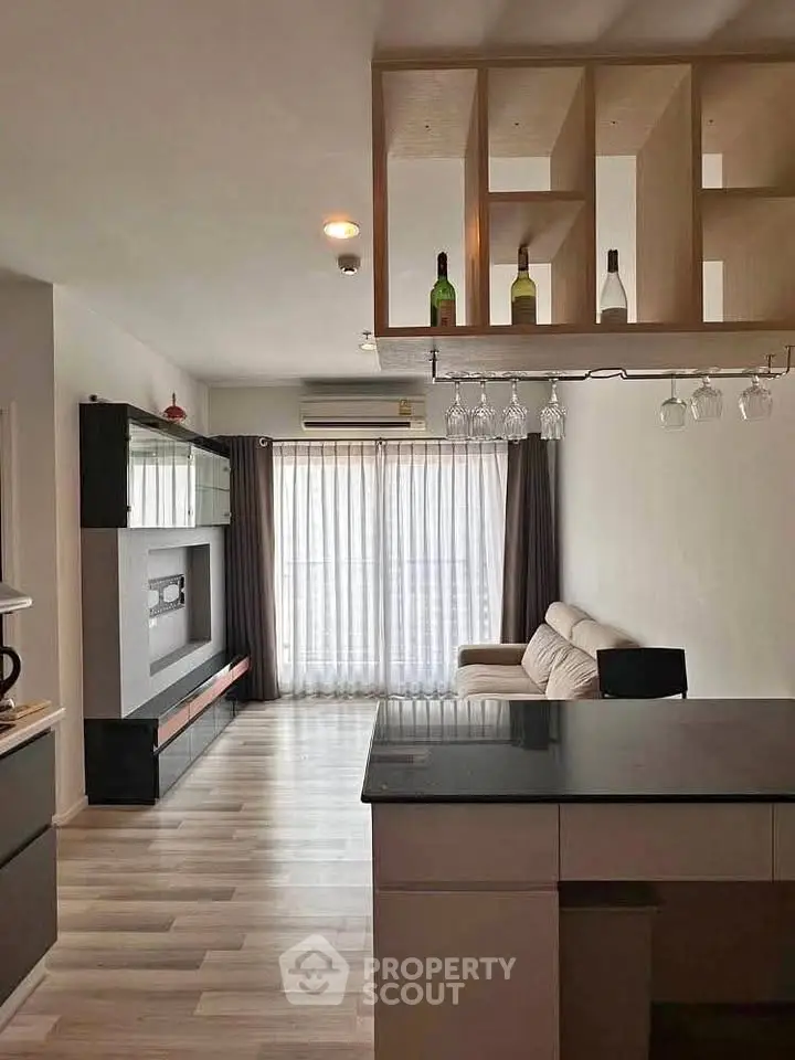 Modern living room with open kitchen and stylish shelving, featuring natural light and contemporary design.