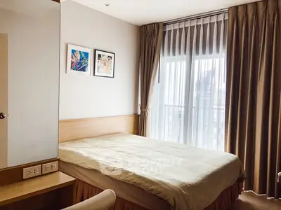 Cozy bedroom with large window and elegant curtains in modern apartment