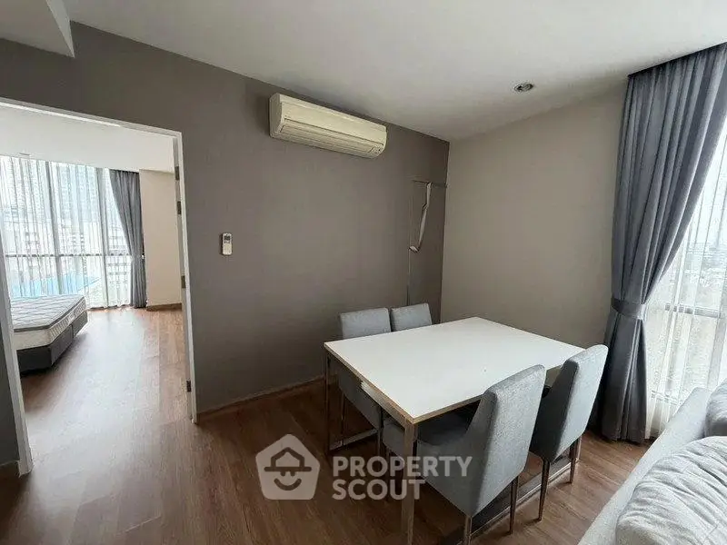 Modern apartment interior with dining area and view into bedroom, featuring sleek furniture and natural light.