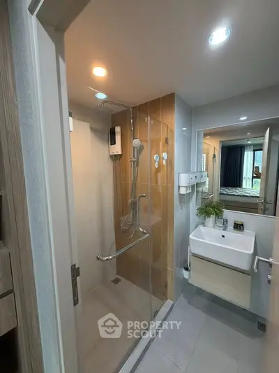 Modern bathroom with glass shower enclosure and stylish sink in contemporary apartment.