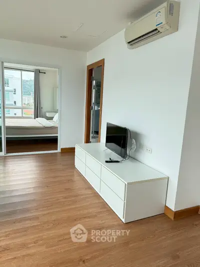 Modern living room with sleek TV stand and air conditioning, adjacent to a cozy bedroom.