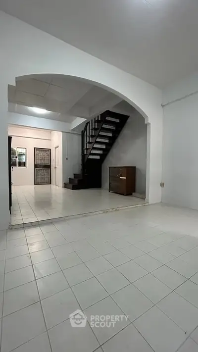 Spacious open-plan living area with modern staircase and tiled flooring, perfect for contemporary living.