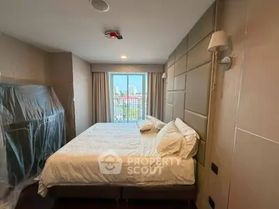 Spacious bedroom with large window and city view, featuring modern decor and cozy bedding.