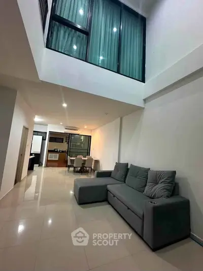 Spacious modern living room with high ceiling and sleek furniture in a contemporary apartment.