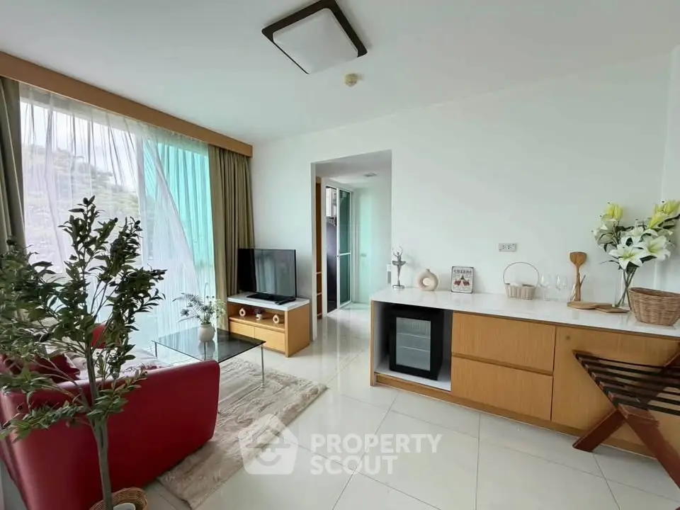 Modern living room with stylish decor and natural light, featuring a cozy seating area and sleek entertainment setup.