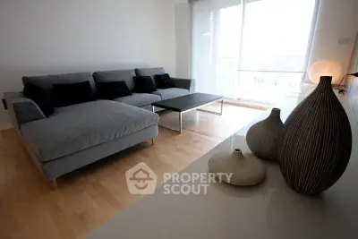 Modern living room with stylish gray sofa and decorative vases, featuring natural light from large windows.