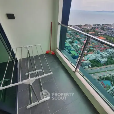 High-rise balcony with stunning ocean view and cityscape, featuring modern glass railing.
