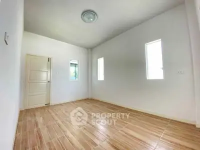 Spacious empty room with wooden flooring and white walls, ideal for customization.