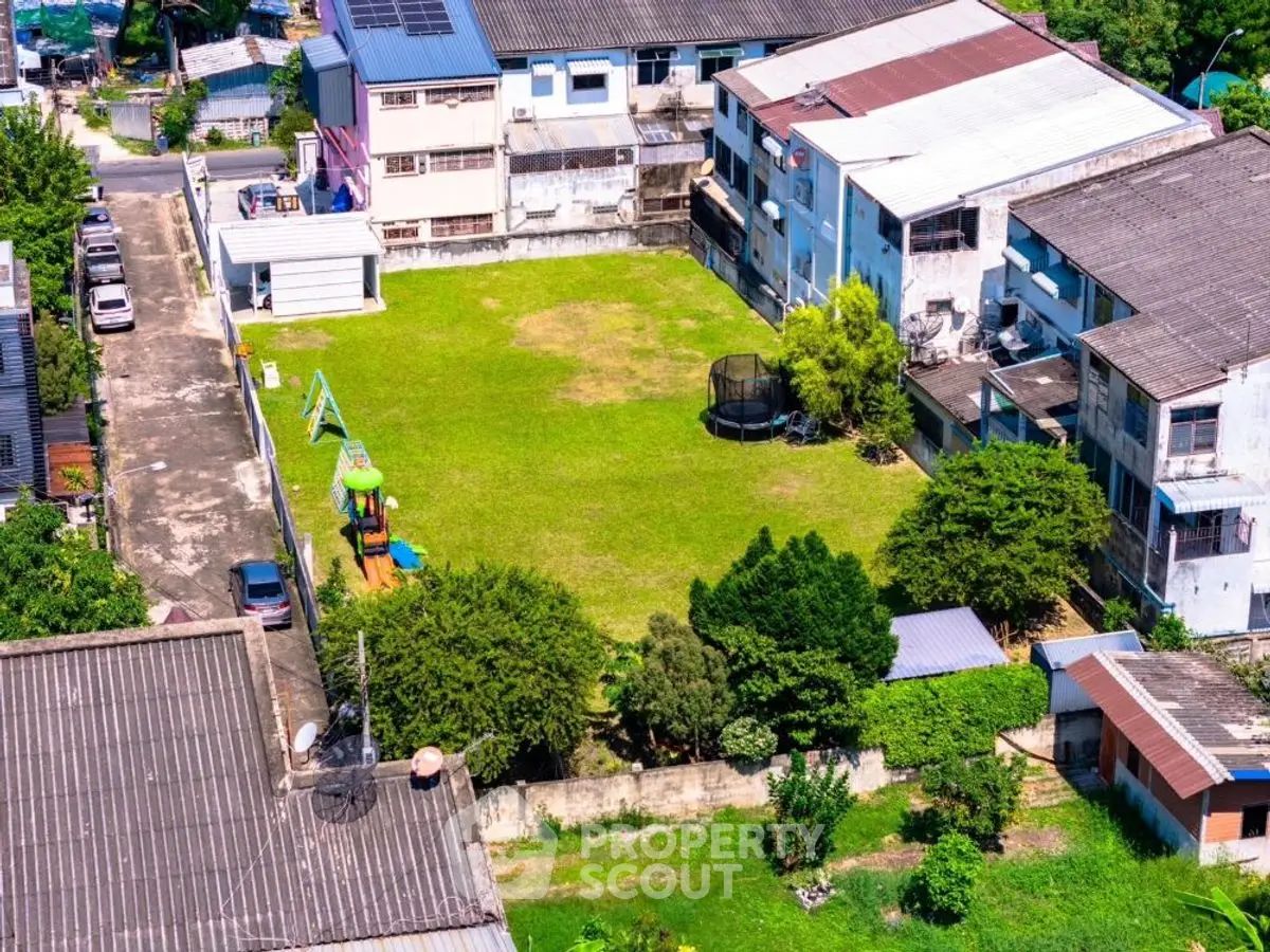 Aerial view of residential complex with green lawn and playground, ideal for families seeking outdoor space.