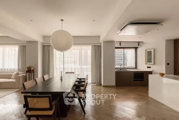 Elegant dining area with modern open kitchen and large windows