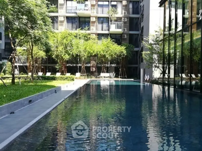 Luxurious modern apartment complex with serene pool and lush greenery