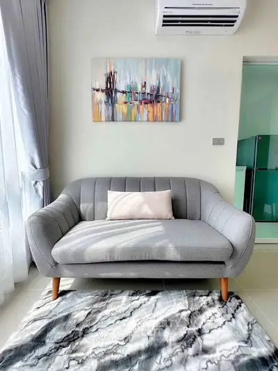 Modern living room with stylish gray sofa, abstract art, and air conditioning unit.