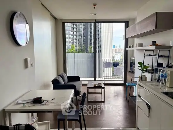 Modern living room with open kitchen and balcony view in urban apartment.