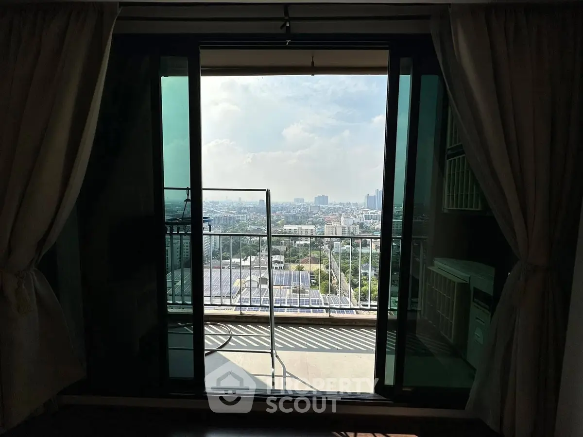 Stunning city view from a high-rise balcony with sliding glass doors and curtains.