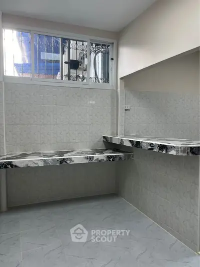 Modern kitchen with marble countertops and tiled walls, featuring a sleek design and ample workspace.