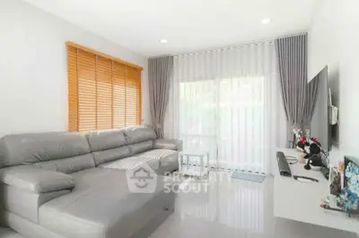Modern living room with sleek grey sofa and large windows for natural light.