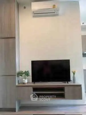 Modern living room with wall-mounted TV and air conditioning unit, featuring sleek wooden cabinetry.