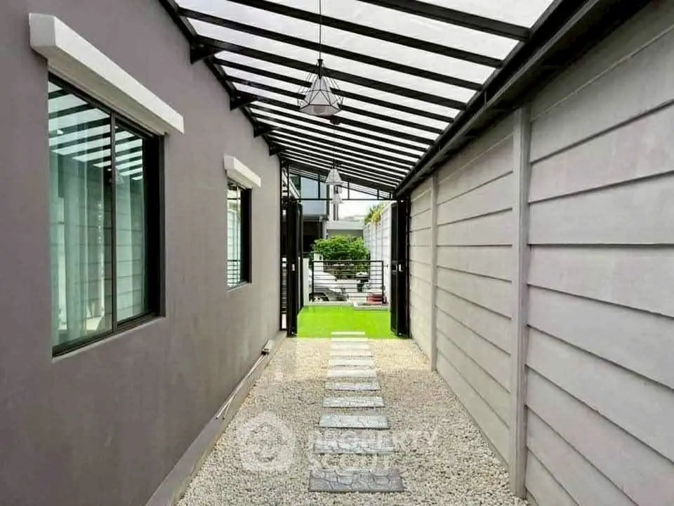 Modern covered walkway with sleek design leading to a lush garden area.
