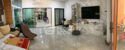 Spacious modern living room with marble flooring and large TV, open layout to dining area.