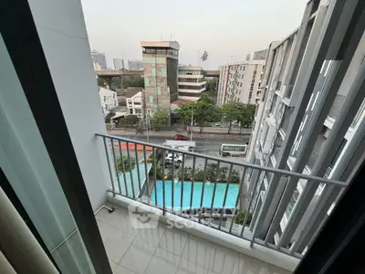 Modern balcony with city view overlooking pool and urban landscape.