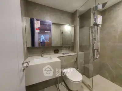 Modern bathroom with sleek fixtures and glass shower enclosure in luxury apartment.