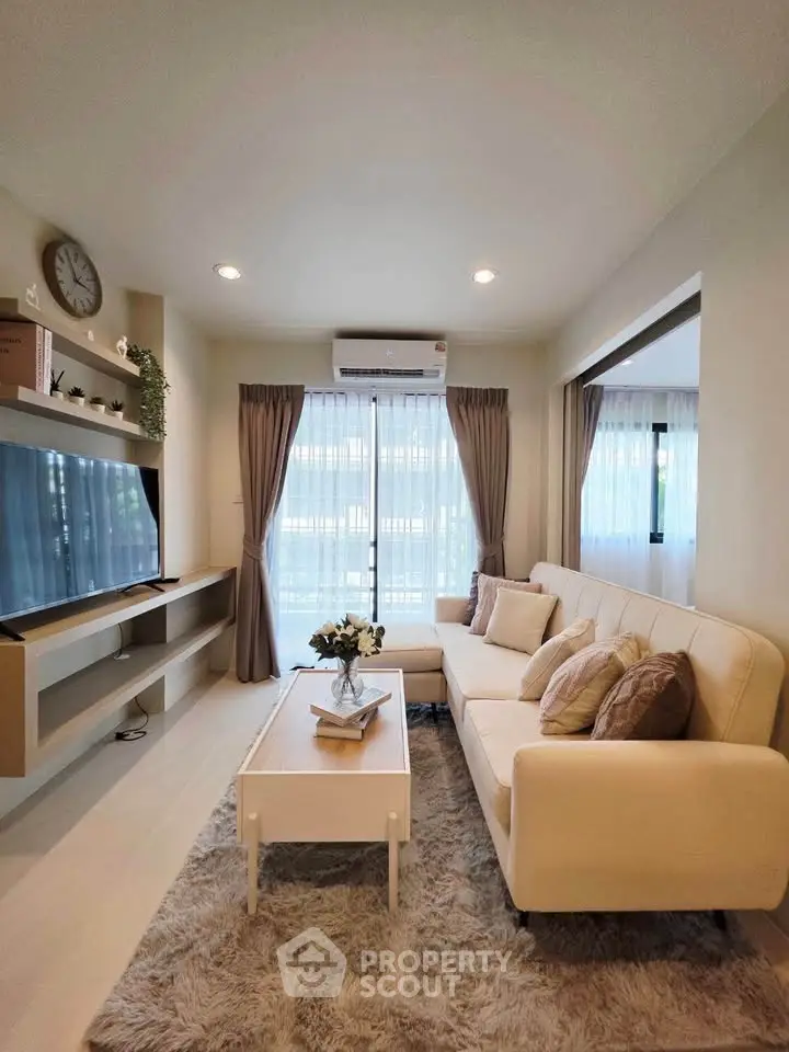Modern living room with cozy sofa, stylish decor, and natural light from large windows.