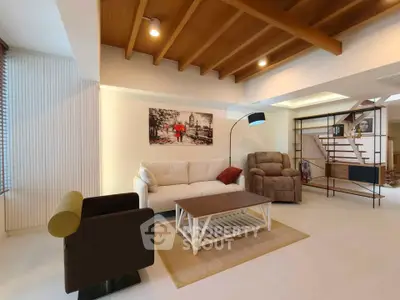 Spacious modern living room with stylish furniture and wooden ceiling beams.