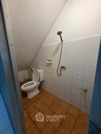 Compact bathroom with sloped ceiling and basic fixtures