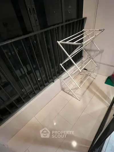 Compact balcony with drying rack and tiled floor, ideal for urban living.