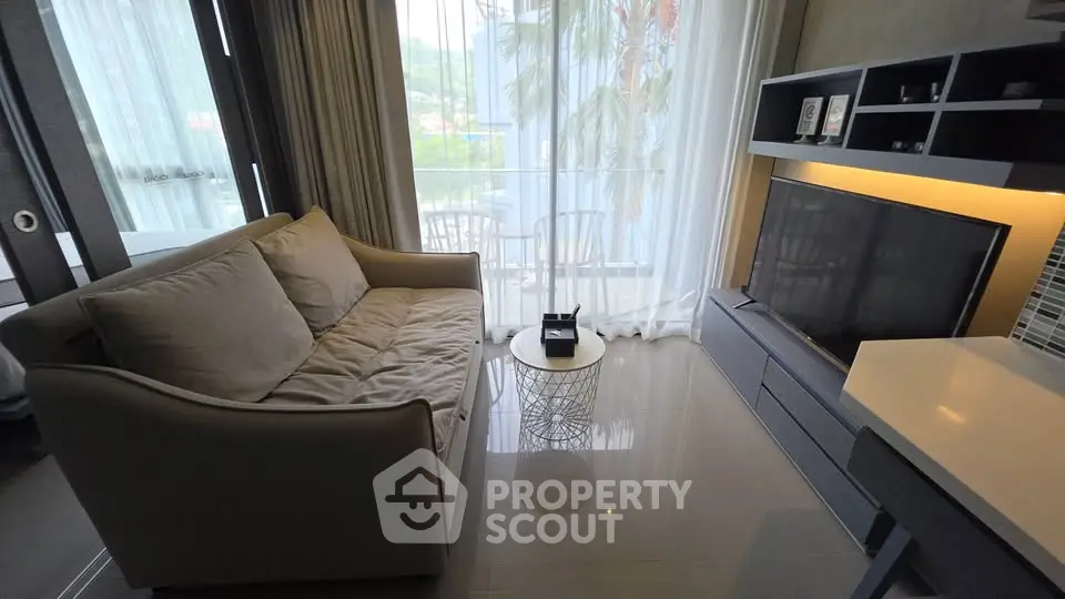 Modern living room with cozy sofa and large TV, featuring a bright balcony view.