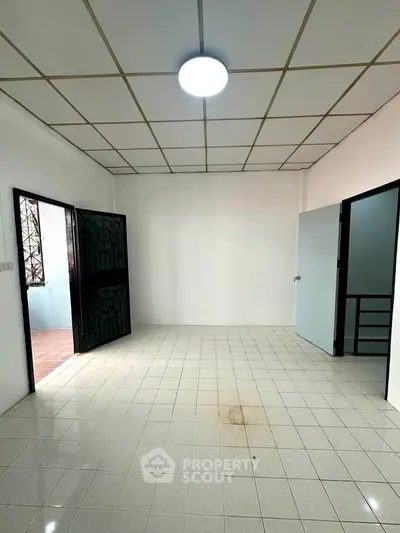 Spacious empty room with tiled floor and natural light, ideal for customization.