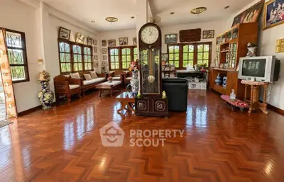 Spacious living room with elegant wooden flooring and classic decor, featuring large windows and ample natural light.