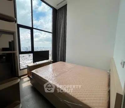Spacious bedroom with floor-to-ceiling windows offering stunning city views.