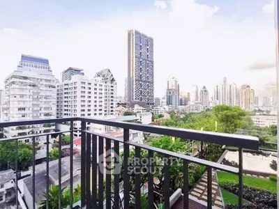 Stunning cityscape view from a modern balcony overlooking skyscrapers and lush greenery.