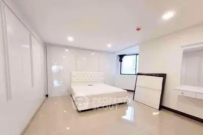 Spacious modern bedroom with elegant white decor and ample natural light.