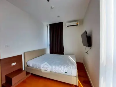 Modern bedroom with minimalist design, featuring a wall-mounted TV and air conditioning unit.