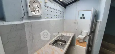 Compact kitchen area with sink and adjacent bathroom in a cozy home setting.