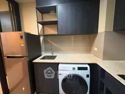 Modern kitchen with sleek cabinets, washing machine, and stainless steel fridge