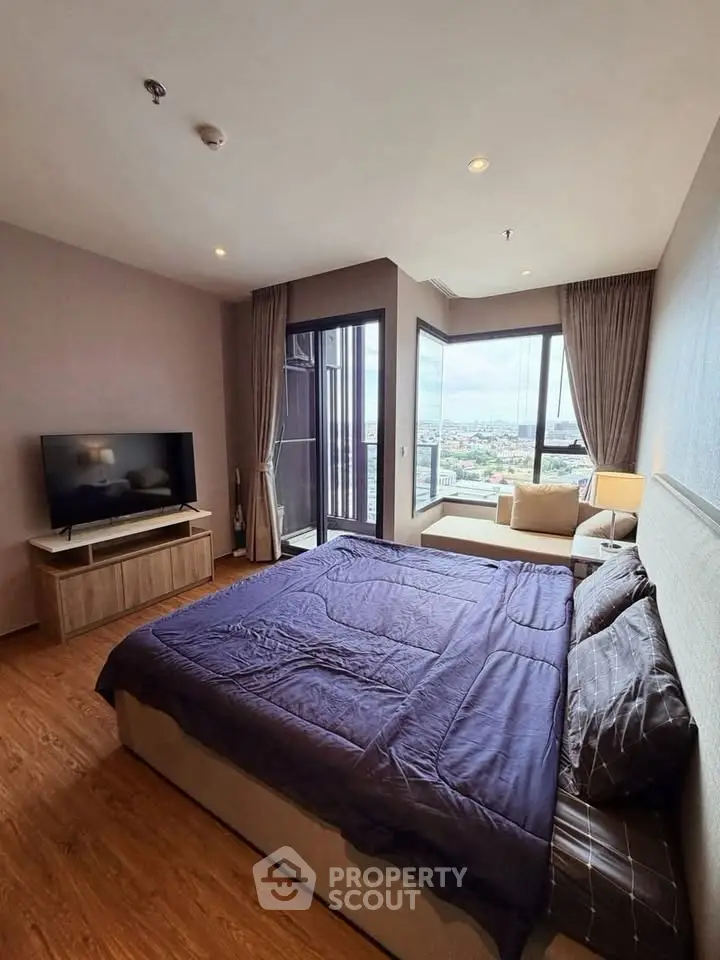 Spacious bedroom with large windows offering stunning city views and modern furnishings.