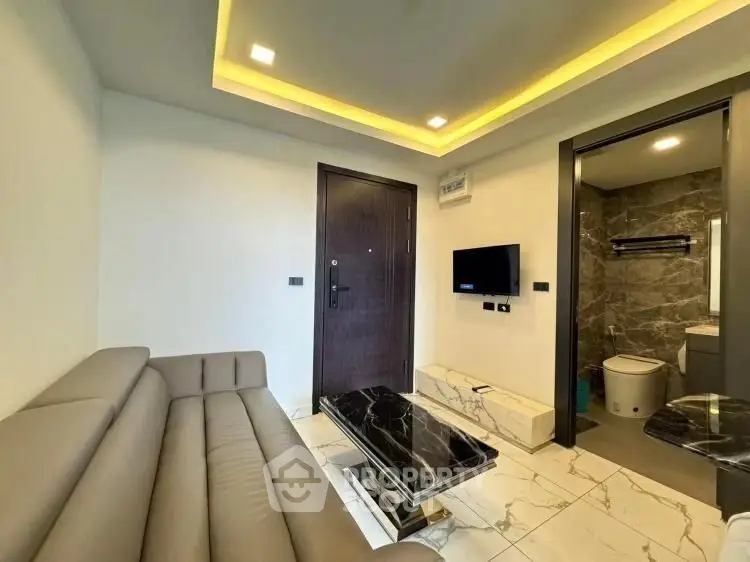 Modern living room with sleek sofa and marble coffee table, adjacent to a stylish bathroom.