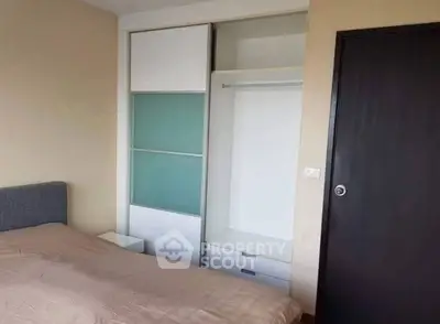 Modern bedroom with sleek sliding closet doors and cozy bed setup.