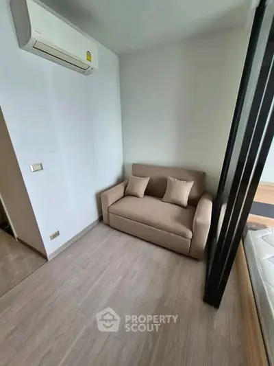 Cozy small living area with sofa and air conditioning in modern apartment.