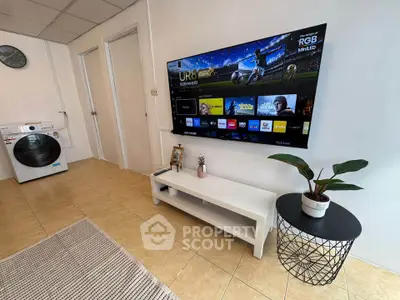Modern living room with wall-mounted TV and stylish furniture, featuring a washing machine in the corner.