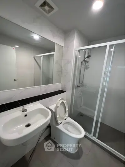 Modern bathroom with sleek fixtures and glass shower enclosure in a contemporary apartment.