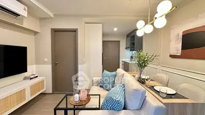 Modern living room with stylish decor and open kitchen layout, featuring elegant lighting and cozy seating.