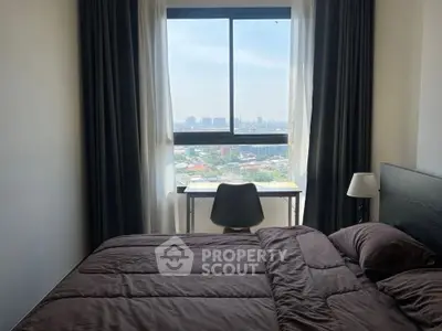 Cozy bedroom with city view, featuring a comfortable bed and a study desk by the window.
