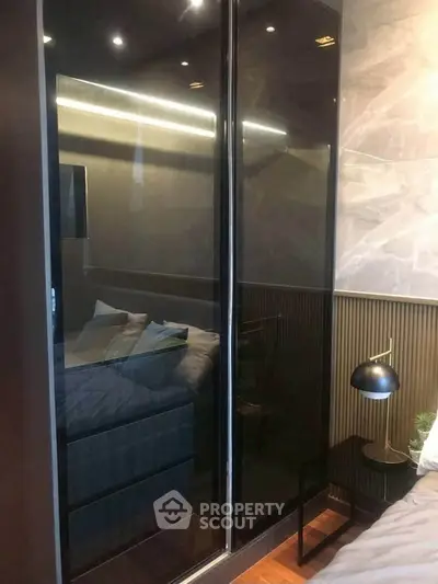 Modern bedroom with sleek glass wardrobe and stylish bedside lamp