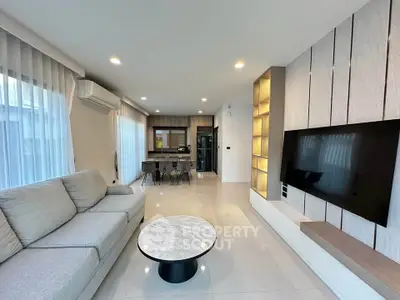 Modern living room with sleek design, featuring a large sofa, wall-mounted TV, and open kitchen layout.